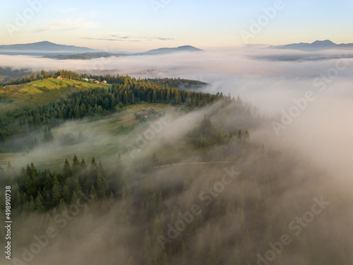 The rays of dawn over the fog in the Ukrainian Carpathians. Aerial drone view.