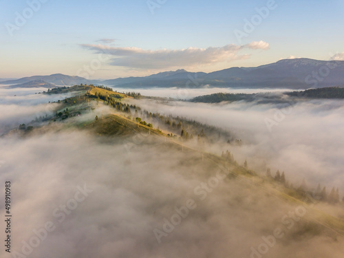 Sunny morning in the foggy Carpathians. A thick layer of fog covers the mountains. Aerial drone view.