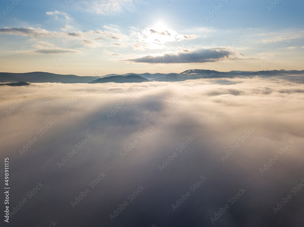 Flight over fog in Ukrainian Carpathians in summer. Mountains on the horizon. A thick layer of fog covers the mountains with a continuous carpet. Aerial drone view. Flight over fog in Ukrainian Carpathians in summer. Mountains on the horizon. A thick layer of fog covers the mountains with a continuous carpet. Aerial drone view.