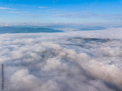 High flight above the clouds in the mountains. Aerial drone view.