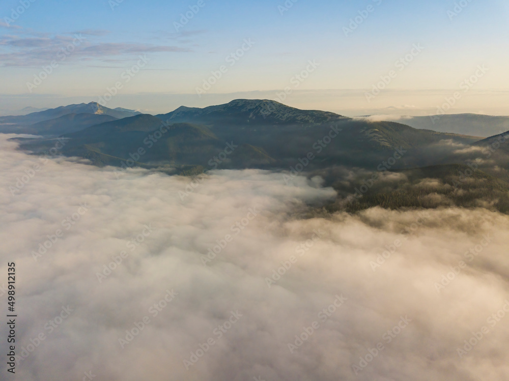 Flight over fog in Ukrainian Carpathians in summer. Mountains on the horizon. Aerial drone view. Flight over fog in Ukrainian Carpathians in summer. Mountains on the horizon. Aerial drone view.