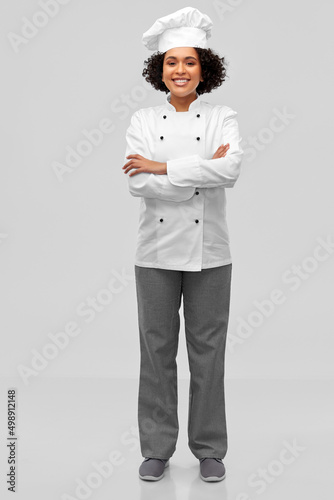 cooking, culinary and people concept - happy smiling female chef in white toque and jacket over grey background