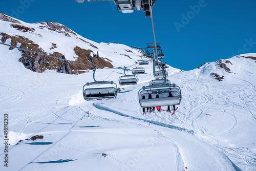 St. Anton am Arlberg. March 10, 2022. Skiers sit in chairlifts on mountain slope at ski resort during beautiful sunny day, Skiers riding skilifts during skiing holiday photo