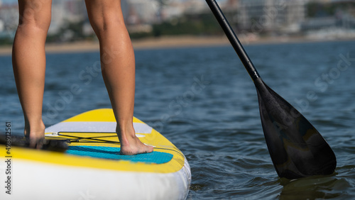 Caucasian woman swims on a SUP board. Close-up of female legs on the surf.