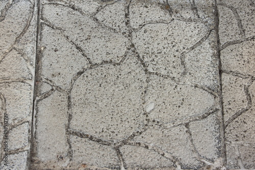 Grey paving slabs with a stone texture and scuffs. Grey vintage background. Street surface.