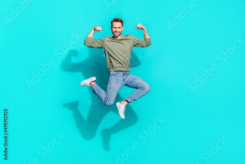 Full length profile photo of confident strong sportsman jump show biceps wear pullover isolated blue color background