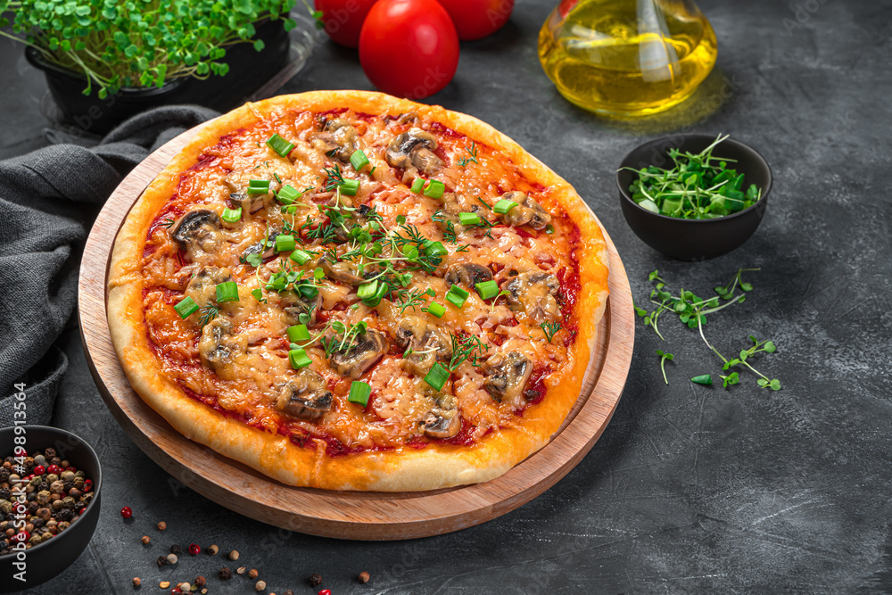 Juicy homemade pizza with mushrooms, cheese, tomatoes and fresh herbs on a black background.