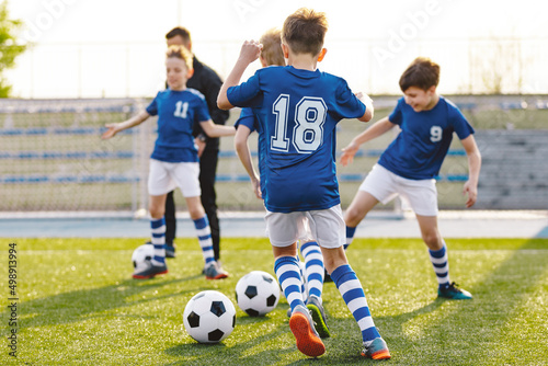 Physical Education Class for School Children. Soccer Education for Young Boys. Young Coach With Kids in Team on Training Unit. Youth Team Coach Training School Boys in Football Soccer © matimix