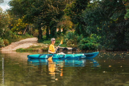 World Tourism Day. Happy smiling girl floating in blue kayak at river. Copy space. The concept of kayaking © _KUBE_