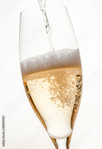 bubbles and foam of different sizes and volumes from golden-colored sparkling wine when pouring a drink into a glass on a light background in a close-up studio