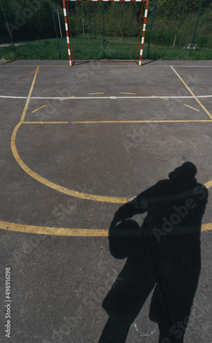 SHADOW OF A PERSON WITH A BALL IN HIS HAND ON THE GROUND OF AN INDOOR SOCCER FIELD