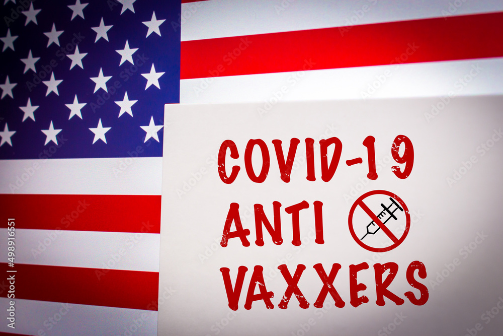 Conceptual keyword COVID-19 ANTI VAXXERS on card on an US flag background. Anti coronavirus vaccination concept.