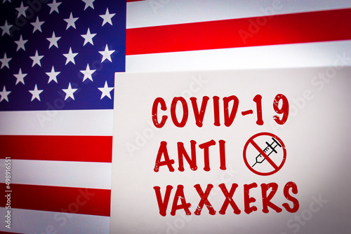Conceptual keyword COVID-19 ANTI VAXXERS on card on an US flag background. Anti coronavirus vaccination concept.