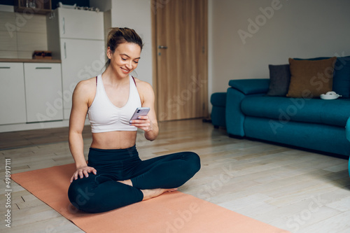 Woman using smartphone after training at home