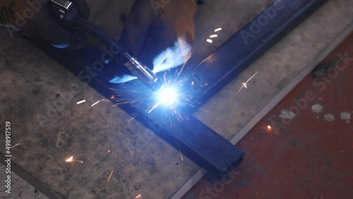 Workers splicing steel with welding ignition in a dim factory workshop