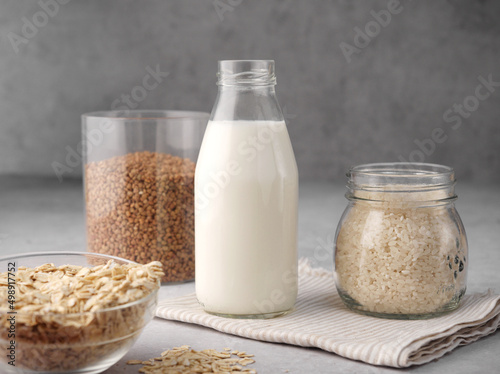 Assortment of organic vegan non-dairy milk from oatmeal, rice, buckwheat in a glass bottle on a gray background. The concept of beverages, healthcare, diet and nutrition. Copy space. Close up. Healthy