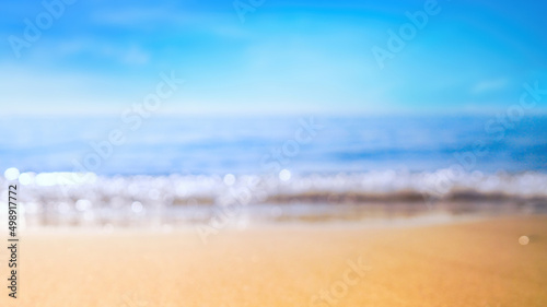 Blurred background of tropical beach with light surf, blue sky and golden sand.