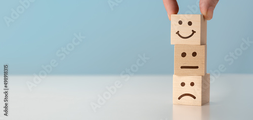 Customer service evaluation and satisfaction survey concepts. client's hand picked happy face smile face symbol on wooden blocks. Emoticon icons face on Wooden Cube , Costumer service concep photo