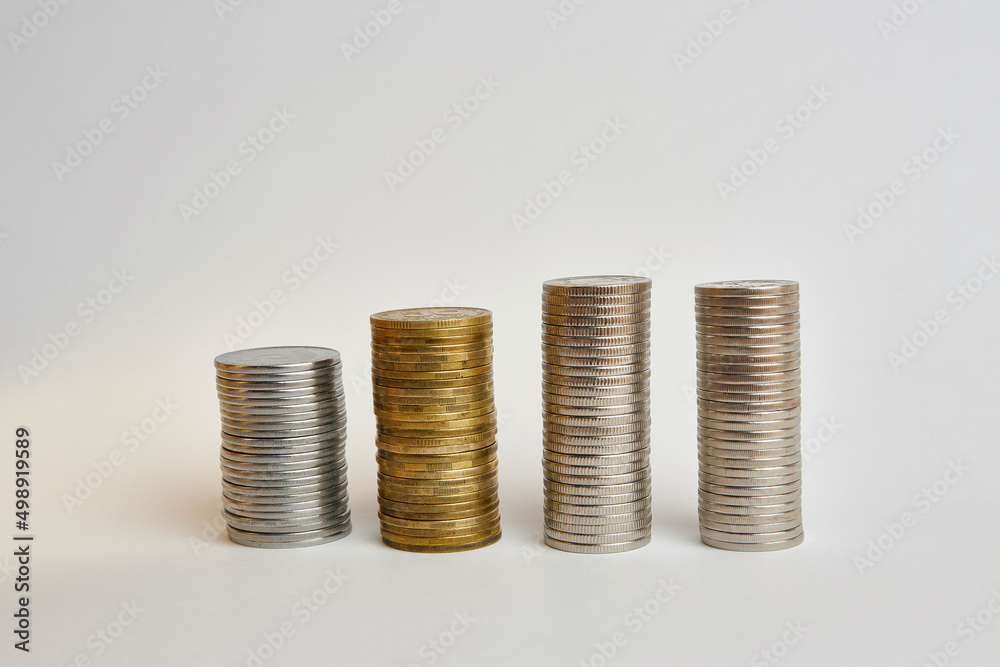 Four towers with coins of different denominations on a white background. Four towers with coins of different denominations on a white background.