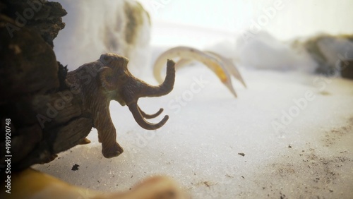 Fototapeta Naklejka Na Ścianę i Meble -  Mammoth in a cold snowy landscape. Mammoth toy in the snow.