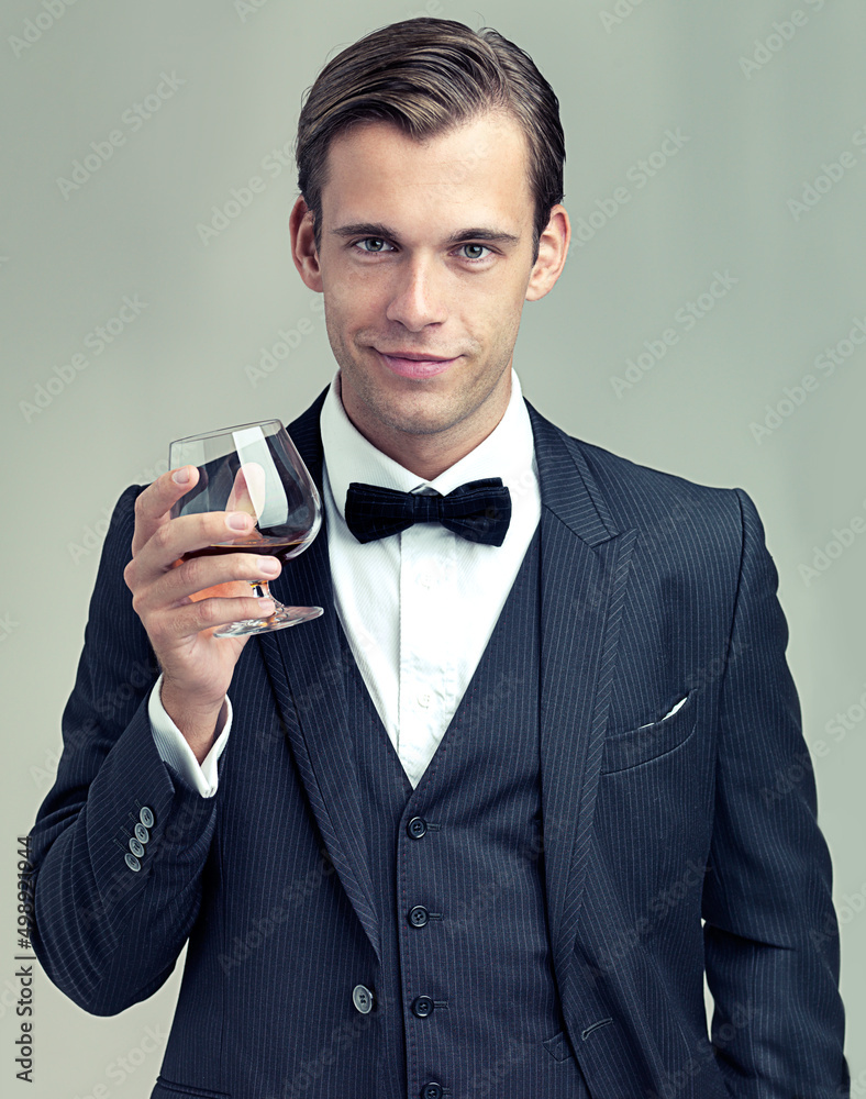 Heres to frivolity. A portrait of a dapper young man with a glass of wine wearing a vintage suit. - obrazy, fototapety, plakaty 