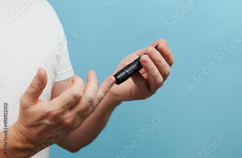 Man with lancet pen doing diabetes test, close-up
