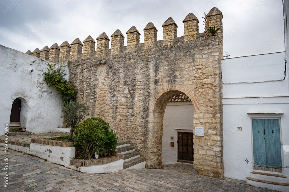 Alley in an ancient medieval village of Vejer in Andalusia with stone wall and turquoise door
