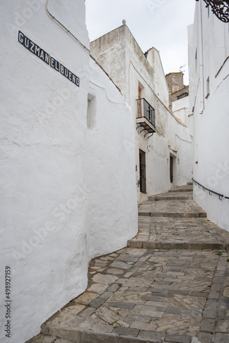 Alley in an ancient medieval village of Vejer in Andalusia with stone wall and turquoise door
