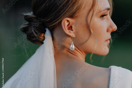  The bride stands with her back to the camera at sunset. Close-up