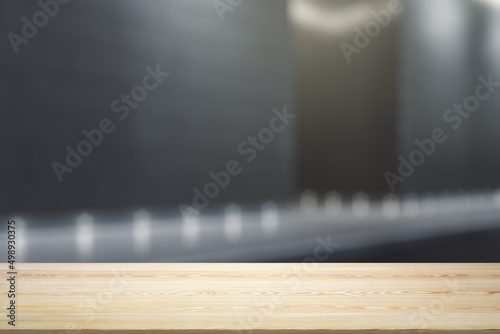 Blank office wooden table with empty space on modern business center exterior background at night, close up, mockup