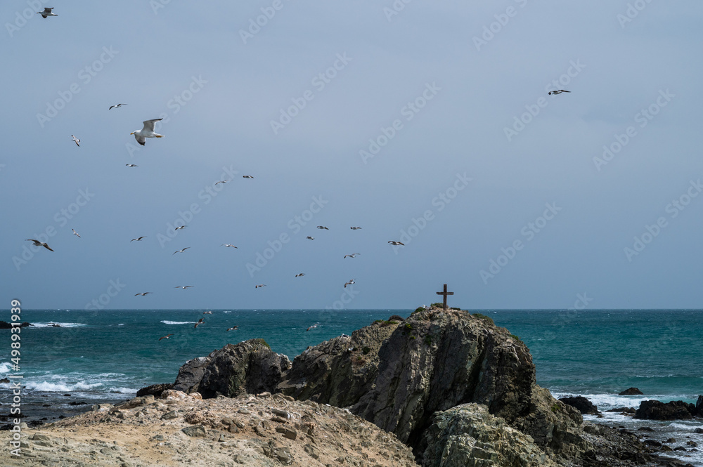Seagulls fly over a cross nailed to a rock near the graveyard of Tabarca. Tabarca is a small islet located in the Mediterranean Sea, close to the town of Santa Pola, Alicante. Seagulls fly over a cross nailed to a rock near the graveyard of Tabarca. Tabarca is a small islet located in the Mediterranean Sea, close to the town of Santa Pola, Alicante.