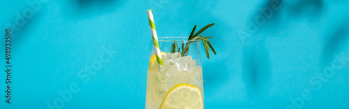 Glass ice lemonade with rosemary on blue background