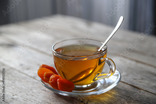 Tea in a glass cup and dried apricots on a saucer. Tea drinking with healthy dry fruits