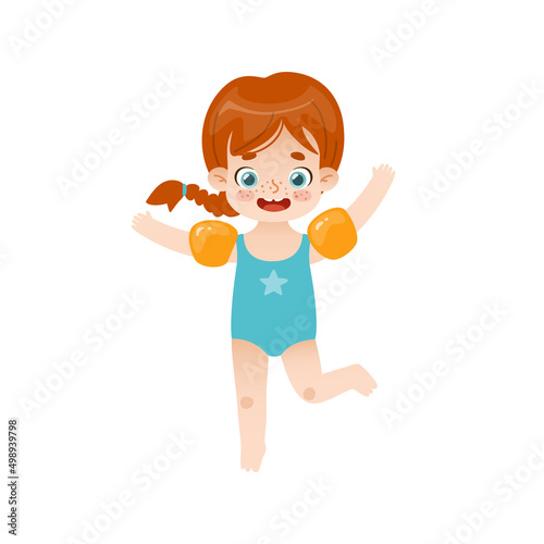 Adorable baby girl jumping with inflatable armbands. Funny red hair girl on summer vacations.