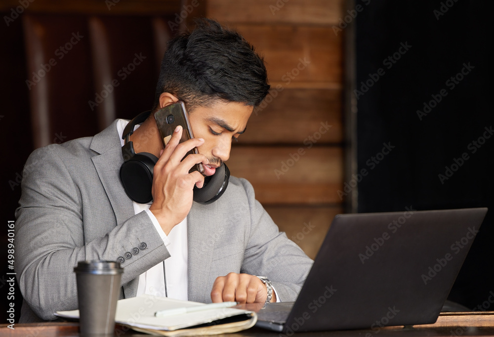 I cant miss this really important business call. Shot of a young businessman checking the time while using a phone at a cafe. I cant miss this really important business call. Shot of a young businessman checking the time while using a phone at a cafe.