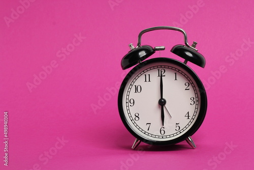 vintage old black alarm clock on pink background