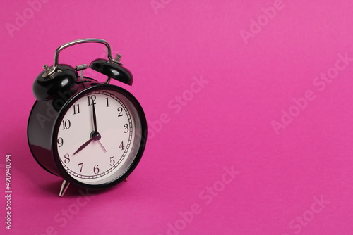 vintage old black alarm clock on pink background