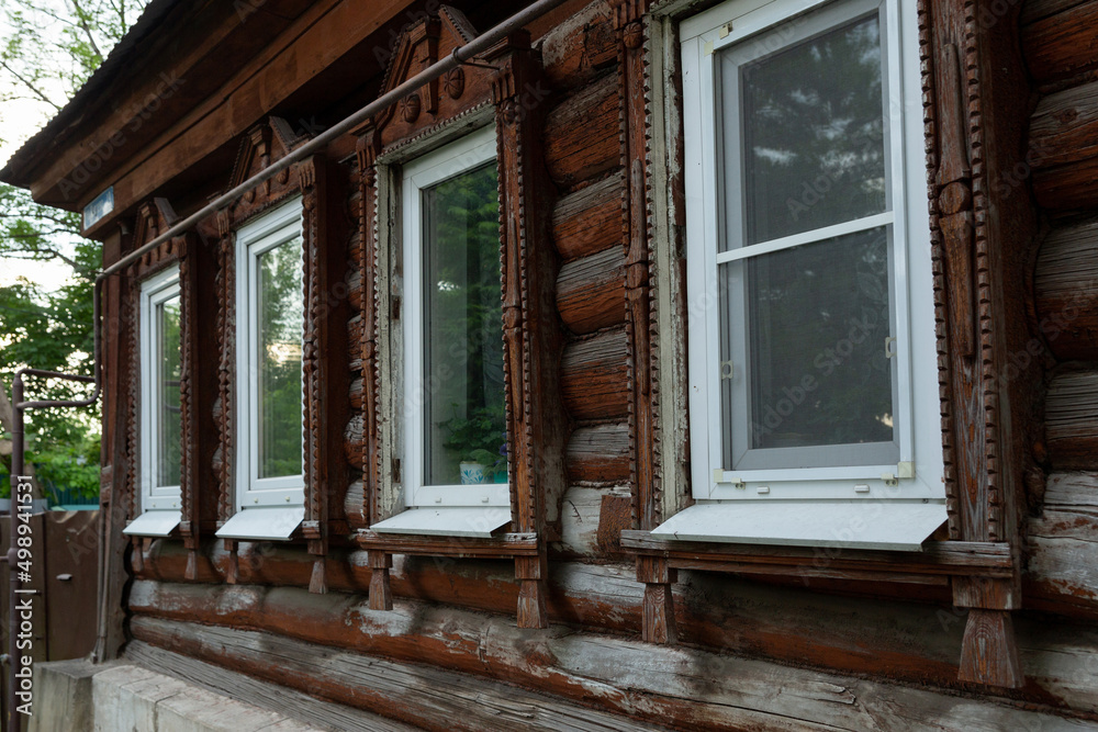 Fototapeta premium The beautiful old windows with beautifully designed platbands window on an old wooden house in the city of Tula