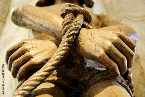 Wooden statue of Jesus with tied hands.