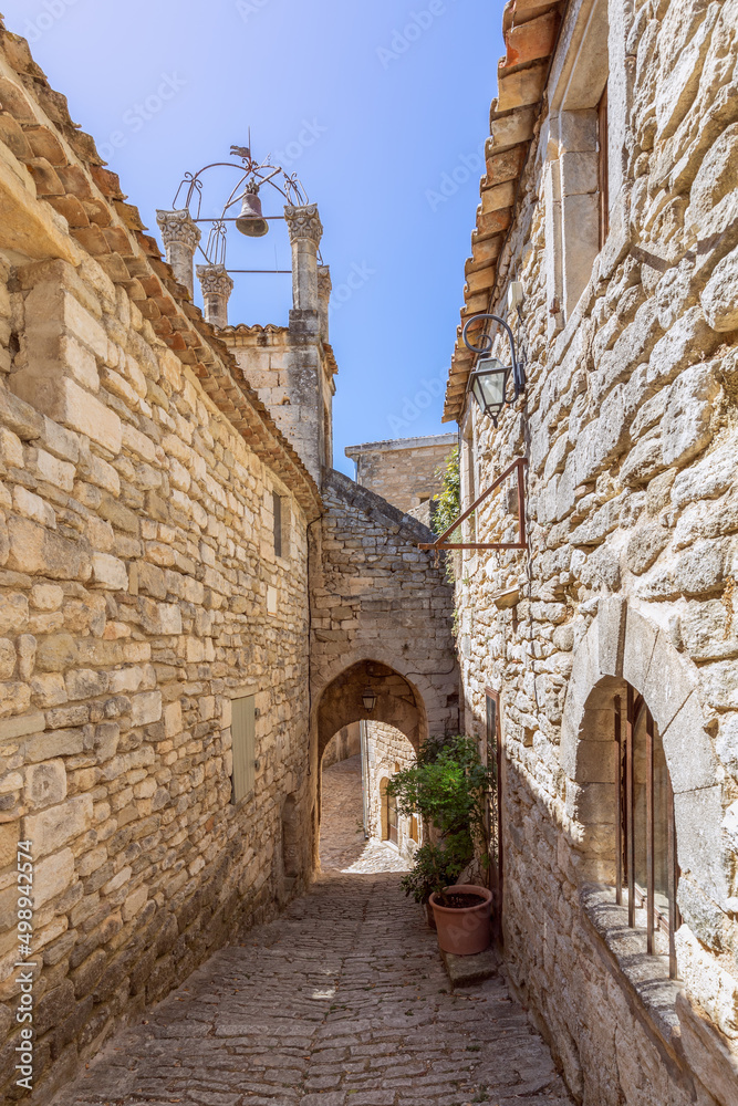 Narrow cobblestone street, vernacular architecture, bell clock tower of Lacoste, Vaucluse, France