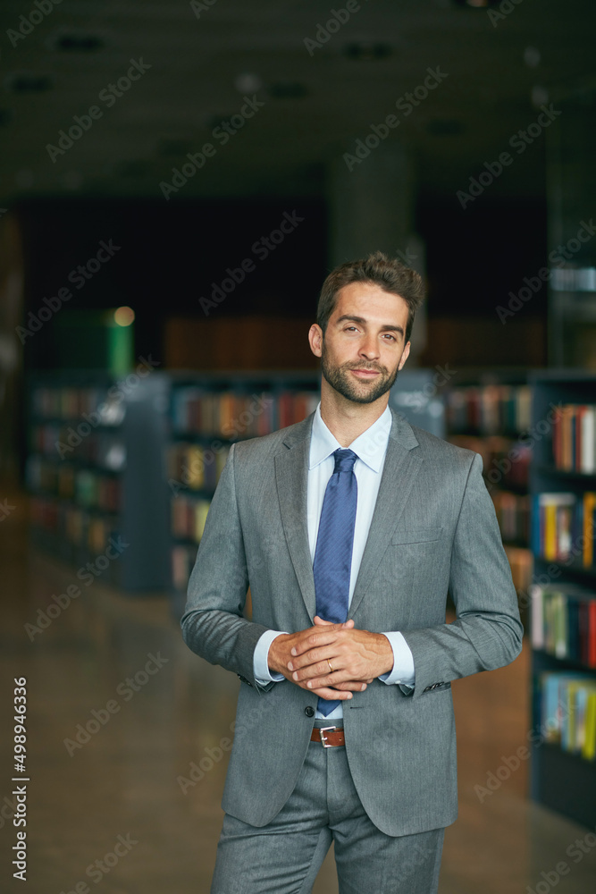 Fototapeta premium Are you ready to share some ideas. Cropped portrait of a handsome young businessman standing with his hands together in an empty library.