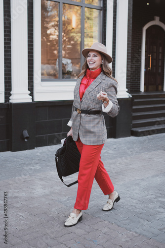 Stylish business woman in jacket and felt hat walks on the city street