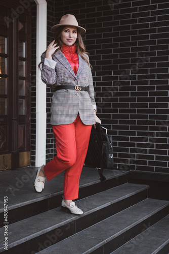 Stylish business woman in jacket and felt hat walks on the city street