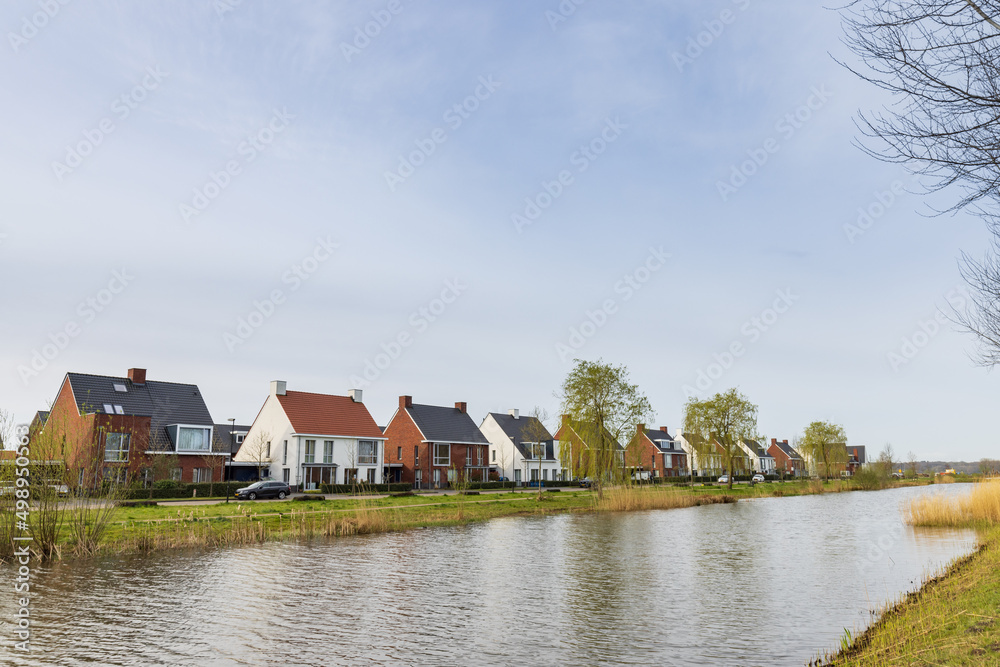 Row of modern newly build family houses along canal in Kortenoord in Wageningen, Gelderland in The Netherlands