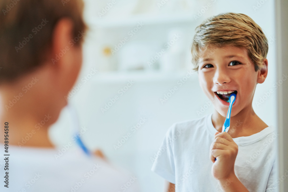 Keeping my teeth strong. Shot of a cheerful young boy looking at his reflection in a mirror while brushing his teeth in the bathroom at home during the day. Keeping my teeth strong. Shot of a cheerful young boy looking at his reflection in a mirror while brushing his teeth in the bathroom at home during the day.