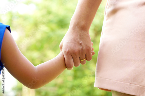 Mother's hand holding a little girl's hand on bokeh background. Love and family concept.