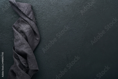 Linen kitchen brawn towel napkin on old black ceramic cement concrete table background. Cooking stone backdrop. Top view with copy space. Flat lay photo