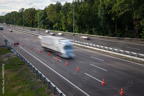 Cars in motion on highway, one lane fenced off for road repair