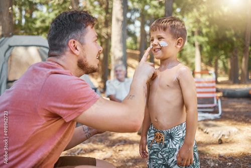 Dont forget your sunscreen. Cropped shot of a handsome young man putting sunblock on his adorable little son while camping in the woods. photo