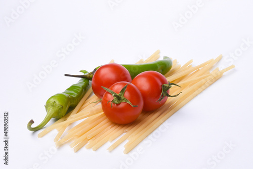 Green peppers, red tomatoes and pasta isolated on white background.